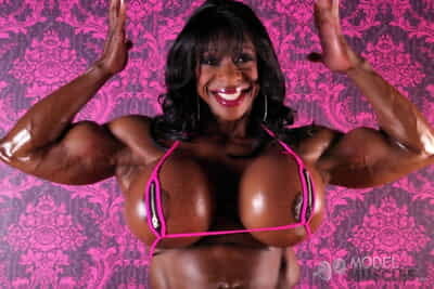 Ebony bodybuilder Yvette Bova unleashes her huge silicone tits while posing