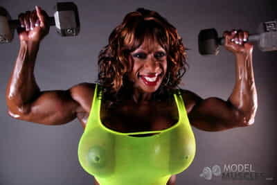 Muscular ebony Yvette Bova lifting weights while flaunting her huge melons
