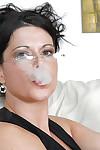 Fully clothed fetish MILF in glasses posing on the sofa and smoking