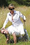 Fully clothed mature femdom in sunglasses abuses her male pet outdoor