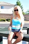 Barbi Sinclair wears glasses as she poses outdoors in high heels and mini skirt.