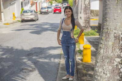 Covered dark brown adolescent Denisse Gomez shows off her alluring face in jean overalls