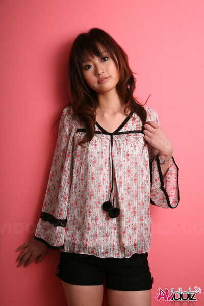 Japanese exemplar with a nice-looking face stands covered against a pink wall