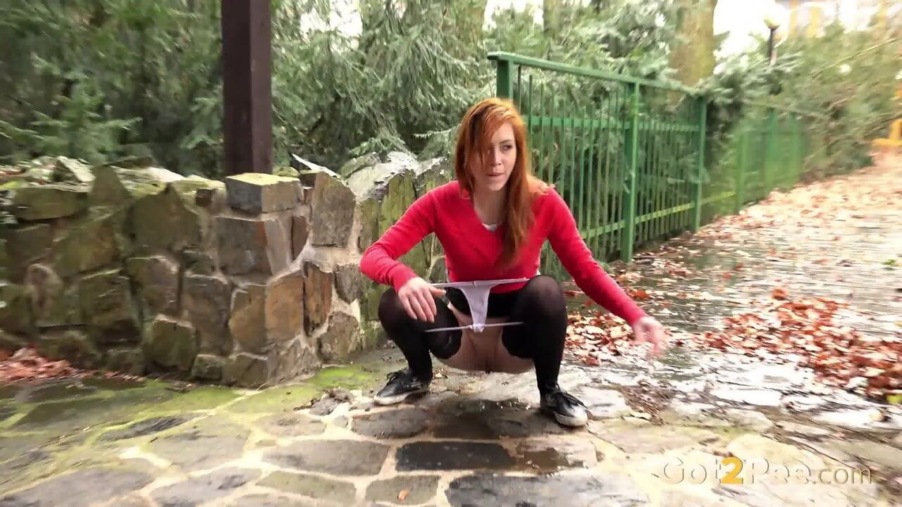 Redhead Sandra lifts her short skirt to take a fancy sticky pee in public