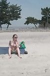 Boobsy سمراء الشعر يأخذ حمام شمس على العامة الشاطئ