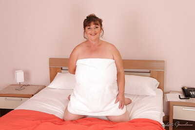 Mature plumper with huge saggy jugs and furry cooter posing on the bed